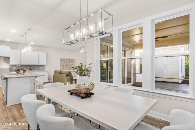 dining space featuring baseboards, ceiling fan, and light wood finished floors