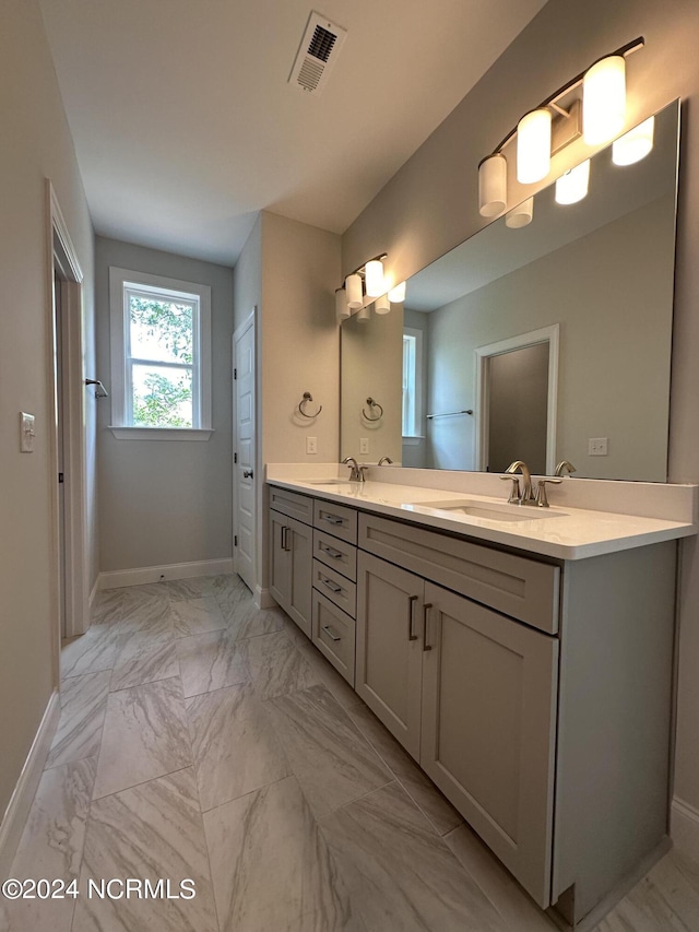 full bathroom with marble finish floor, double vanity, a sink, and visible vents