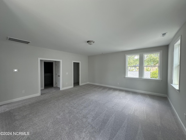 carpeted spare room featuring visible vents and baseboards