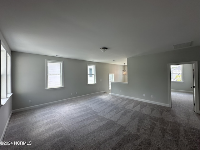 carpeted empty room featuring baseboards and visible vents