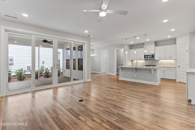 kitchen with an island with sink, light hardwood / wood-style flooring, and ceiling fan