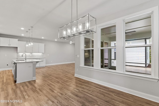 kitchen featuring hanging light fixtures, white cabinetry, and light wood-type flooring