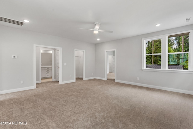 unfurnished bedroom with connected bathroom, light colored carpet, and ceiling fan