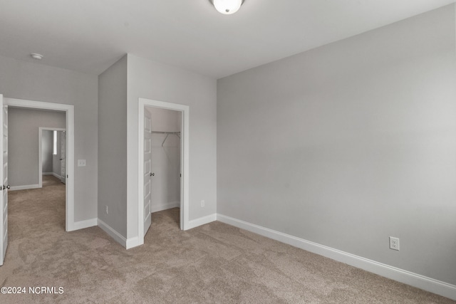 unfurnished bedroom featuring light carpet, a closet, and a walk in closet