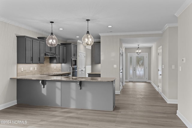 kitchen featuring stainless steel microwave, a kitchen breakfast bar, crown molding, hanging light fixtures, and kitchen peninsula