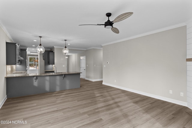 kitchen featuring pendant lighting, kitchen peninsula, sink, and dark stone counters