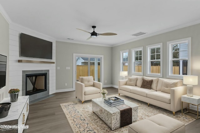 unfurnished living room featuring ceiling fan, a large fireplace, hardwood / wood-style floors, and ornamental molding