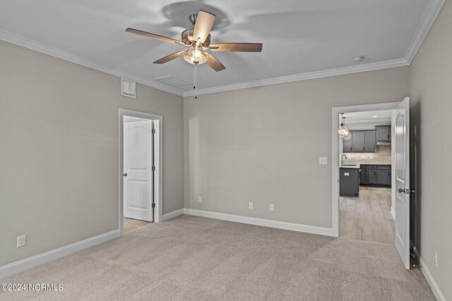 unfurnished room featuring ceiling fan, sink, light colored carpet, and ornamental molding