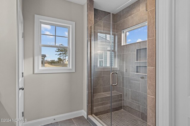 bathroom with tile patterned floors, a wealth of natural light, and a shower with door