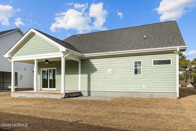 rear view of property featuring a yard and ceiling fan