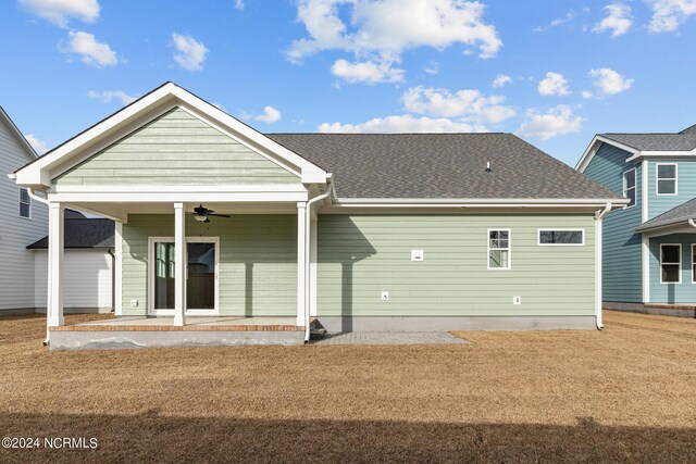 rear view of property featuring ceiling fan and a lawn