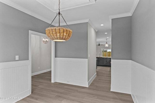 dining space with hardwood / wood-style floors, ornamental molding, sink, and an inviting chandelier