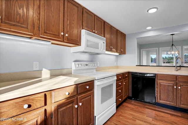 kitchen featuring white appliances, hanging light fixtures, wood-type flooring, and sink