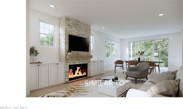 living area with a wealth of natural light, a fireplace, light wood finished floors, and recessed lighting