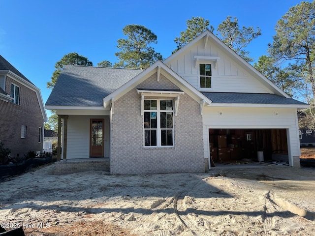 view of front facade featuring concrete driveway, brick siding, board and batten siding, and roof with shingles