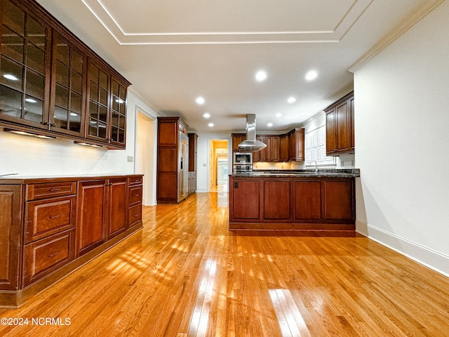 kitchen featuring dark stone counters, sink, light hardwood / wood-style flooring, wall chimney range hood, and ornamental molding