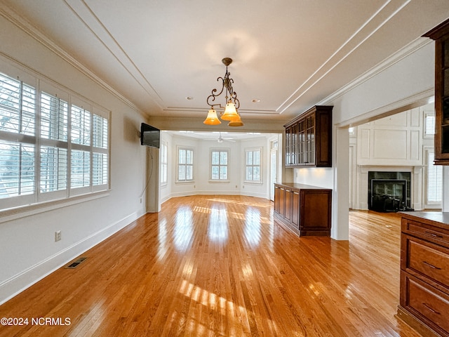 unfurnished living room featuring a fireplace, ornamental molding, light hardwood / wood-style floors, and ceiling fan with notable chandelier