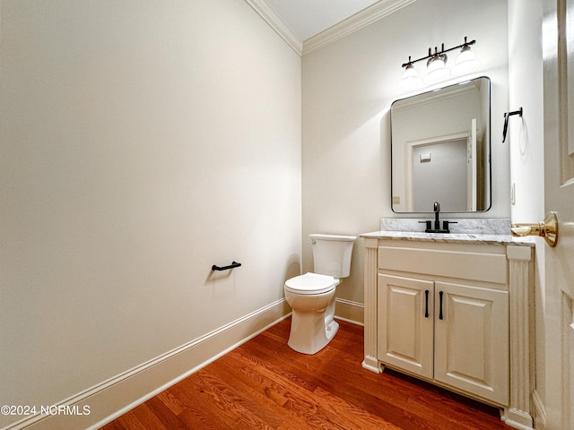 bathroom with toilet, vanity with extensive cabinet space, hardwood / wood-style flooring, and ornamental molding