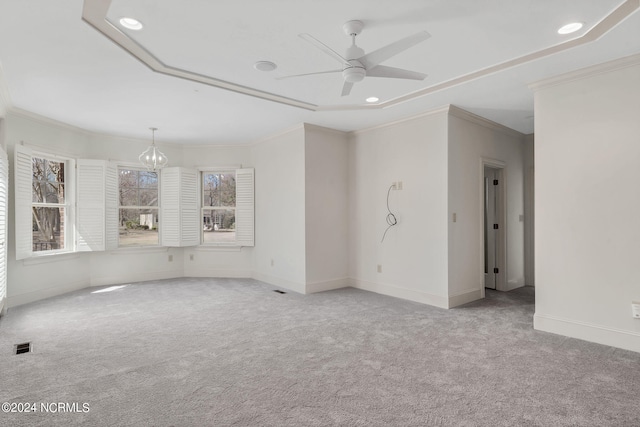 carpeted spare room featuring ceiling fan with notable chandelier and crown molding