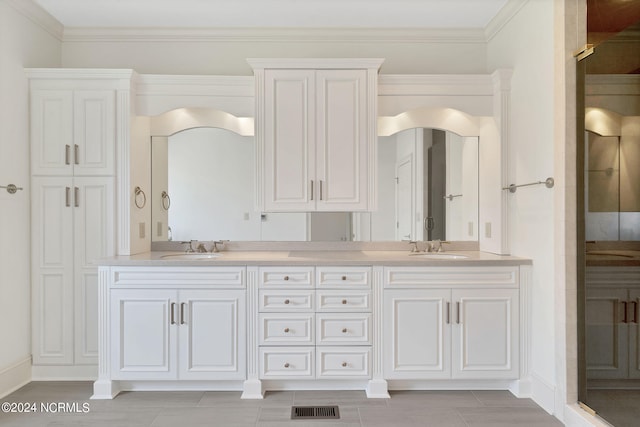 bathroom with crown molding, double sink, and vanity with extensive cabinet space