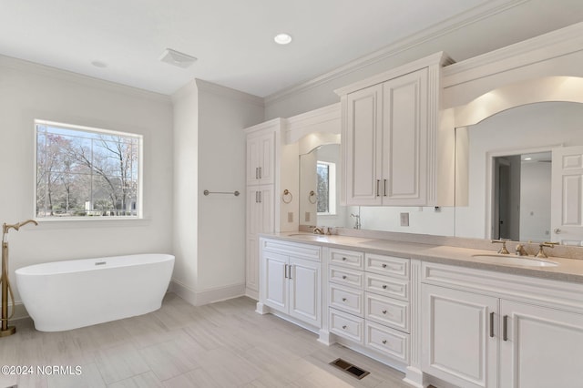 bathroom featuring tile flooring, crown molding, large vanity, dual sinks, and a tub