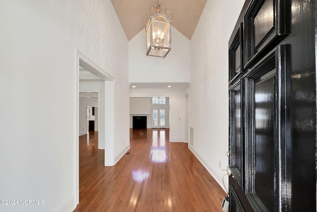 corridor featuring light hardwood / wood-style flooring, a notable chandelier, and high vaulted ceiling