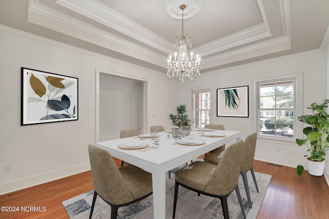 dining room featuring dark hardwood / wood-style flooring, ornamental molding, an inviting chandelier, and a tray ceiling