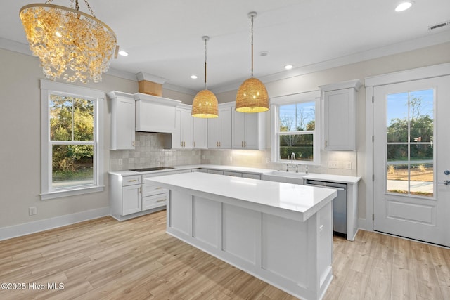 kitchen with white cabinetry, a kitchen island, stainless steel dishwasher, and decorative light fixtures