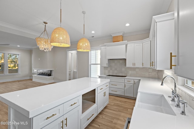 kitchen featuring pendant lighting, a kitchen island, white cabinetry, and sink