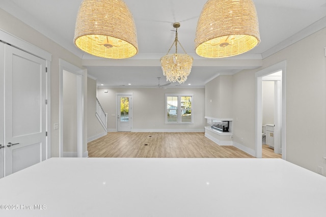 interior space with a multi sided fireplace, ceiling fan with notable chandelier, light hardwood / wood-style floors, and ornamental molding