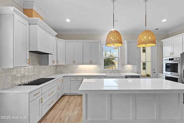 kitchen with decorative light fixtures, black electric cooktop, white cabinetry, and sink