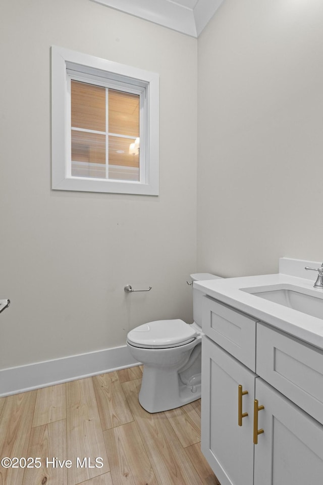 bathroom with hardwood / wood-style floors, vanity, toilet, and crown molding