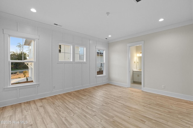 spare room with light wood-type flooring and crown molding