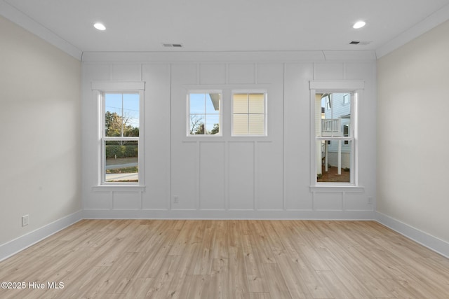 empty room with light hardwood / wood-style floors and crown molding