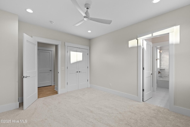 unfurnished bedroom featuring ceiling fan, a closet, light colored carpet, and ensuite bath