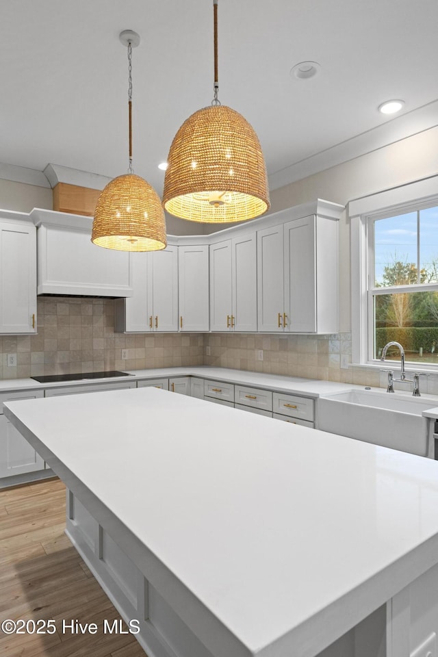 kitchen with white cabinetry, decorative backsplash, stovetop, and sink