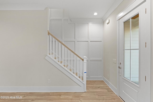 foyer featuring light wood-type flooring and ornamental molding