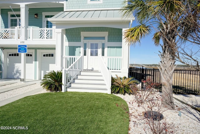 doorway to property with a garage, a yard, and covered porch