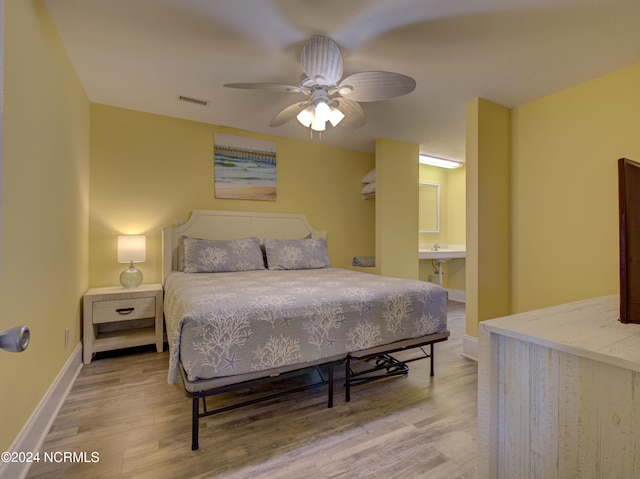 bedroom featuring light hardwood / wood-style floors, ceiling fan, and ensuite bathroom