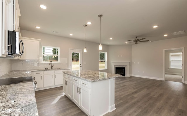 1225 Mandevilla Dr SE, Bolivia, NC 28422 - kitchen featuring stainless steel microwave, a sink, ceiling fan, a fireplace with flush hearth, and tasteful backsplash