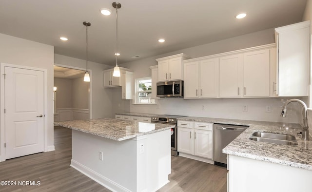 1225 Mandevilla Dr SE, Bolivia, NC 28422 - kitchen with stainless steel appliances, a sink, wood finished floors, white cabinets, and a center island