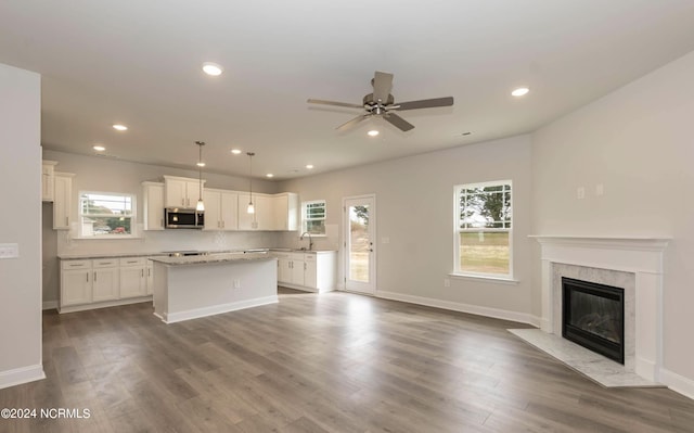 1225 Mandevilla Dr SE, Bolivia, NC 28422 - kitchen with stainless steel microwave, a kitchen island, white cabinets, open floor plan, and recessed lighting