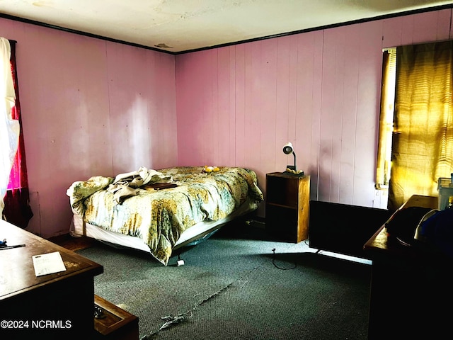 bedroom with wood walls and dark carpet