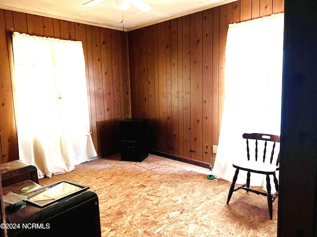 living area with ceiling fan and wood walls