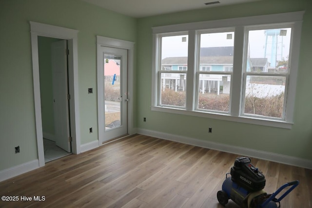 empty room featuring visible vents, light wood-style flooring, and baseboards