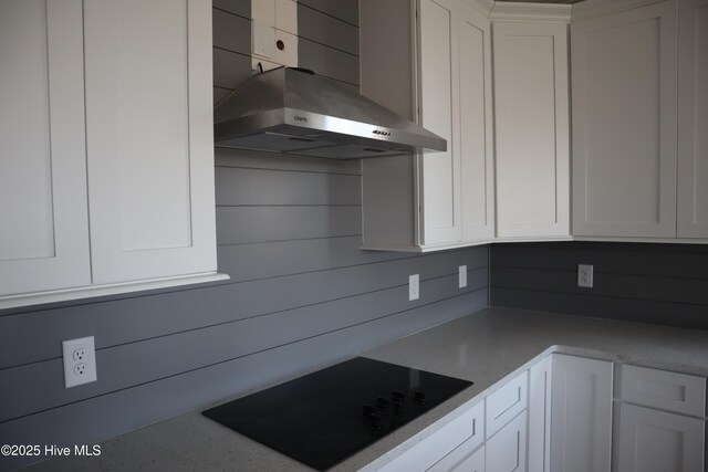 kitchen with white cabinets, light countertops, wall chimney range hood, and black electric stovetop