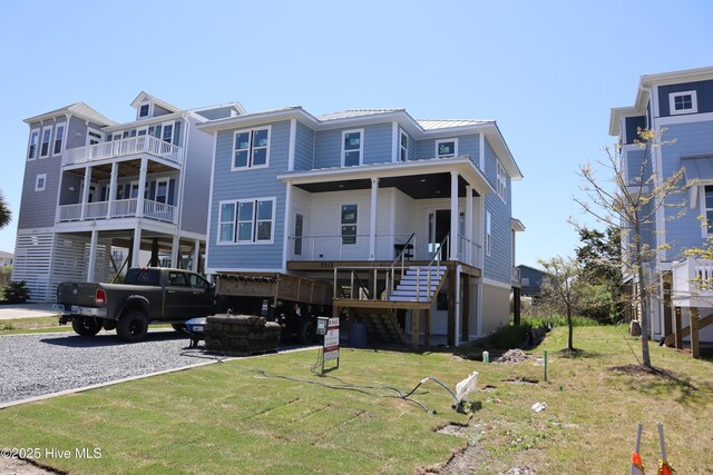 view of front of property with driveway, a front yard, stairs, and metal roof