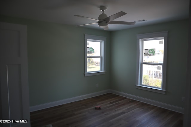 empty room featuring visible vents, baseboards, ceiling fan, and dark wood-style flooring