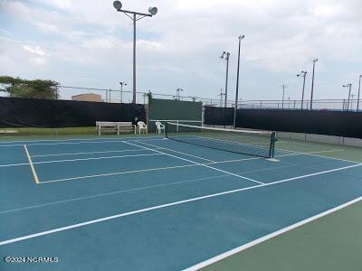 view of tennis court with community basketball court and fence