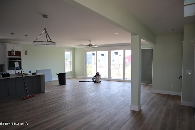 unfurnished living room with wood finished floors, baseboards, and ceiling fan